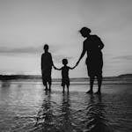 Monochrome Photo of People Holding Hands While Standing on Beach
